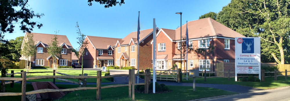 Four modern detached houses on an estate, with a sign reading: Coming soon, a development of three-, four-, and five-bedroom houses